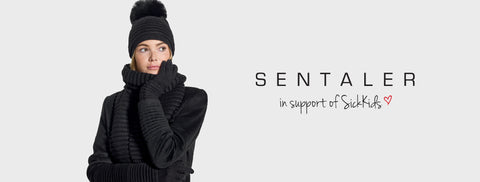 Sentaler Adult Ribbed Hat With Oversized Fur Pompon, Ribbed Scarf and Ribbed Gloves featured in Baby Alpaca and available in Black. Seen from front above the waist on model.