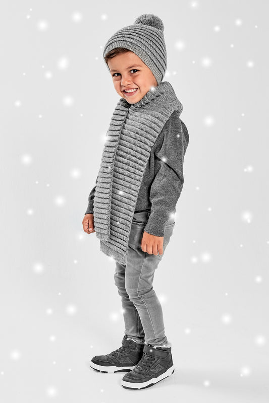 Sentaler Kids (1-5 Years) Ribbed Hat with Oversized Knit Pompon and Ribbed Scarf featured in Baby Alpaca and available in Grey. Seen from front with snow effect.
