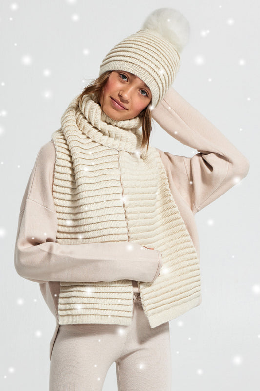 Sentaler Kids (6-14 Years) Ribbed Hat with Oversized Fur Pompon and Ribbed Scarf featured in Baby Alpaca and available in Ivory. Seen from front with snow effect.