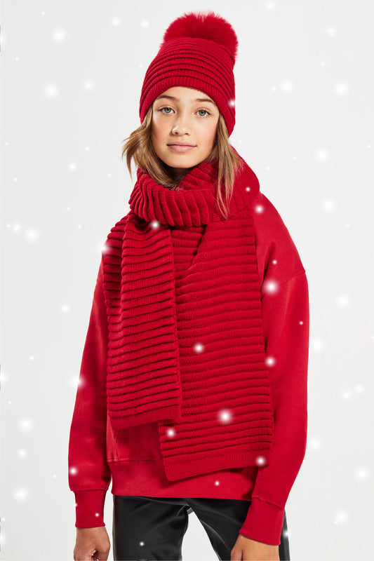 Sentaler Kids (6-14 Years) Ribbed Hat with Oversized Fur Pompon and Ribbed Scarf featured in Baby Alpaca and available in Red. Seen from front with snow effect.